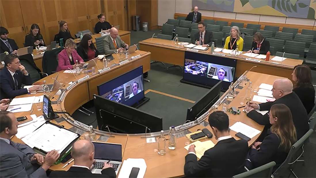 Committee members and invited speakers sit around a large table